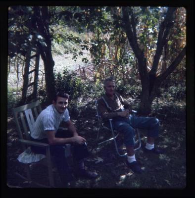 Two men sitting under trees