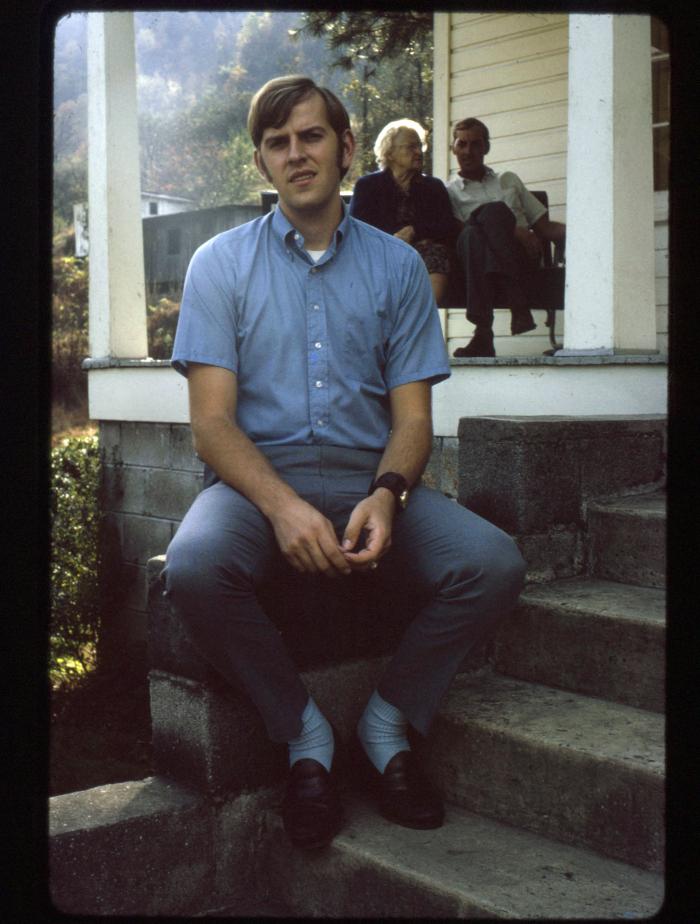 Portrait of Gregory Fields with family on porch in background