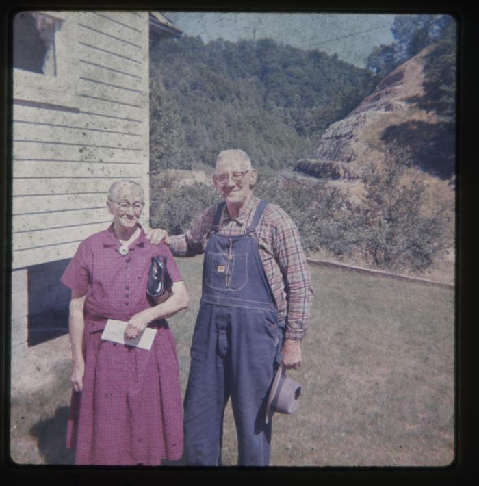 Man and woman standing beside a white house