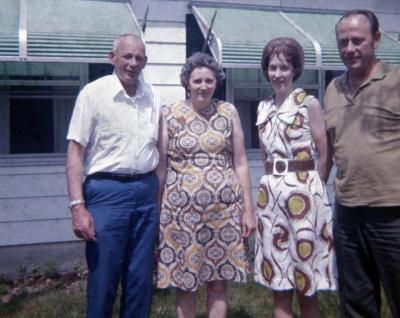 Two men and two women standing in front of a white house
