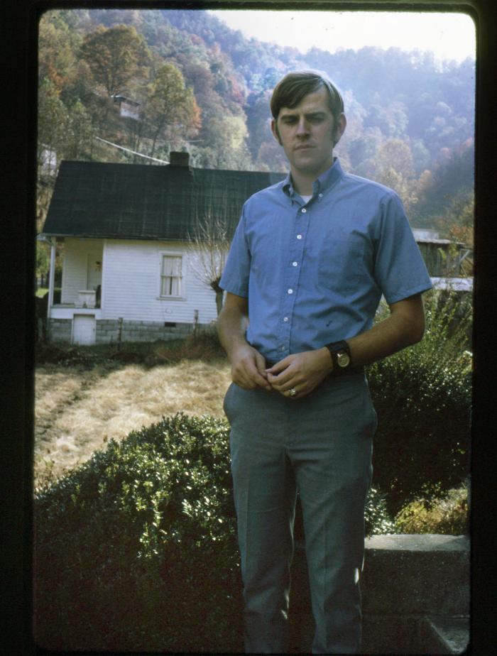 Man standing outdoors with a white house in the background