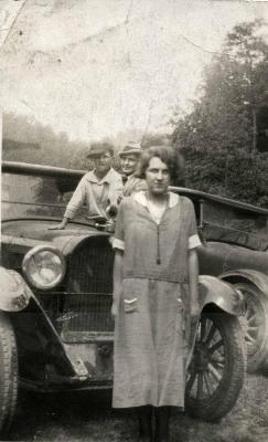 Man, woman, and boy in front of car
