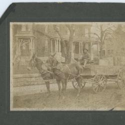 Man driving horse-drawn cart down main street