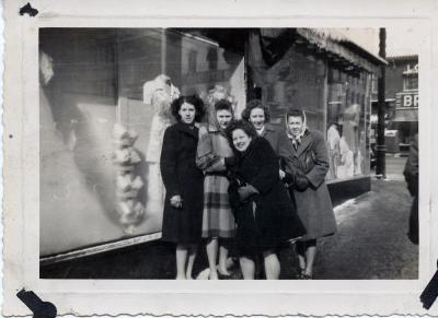 Group of women posing for photo in front of store windows