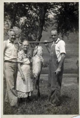Two men and a woman holding up a caught fish