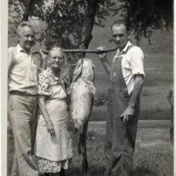 Two men and a woman holding up a caught fish