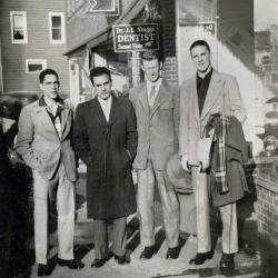 Four men standing in front a building