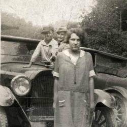 Man, woman, and boy in front of car