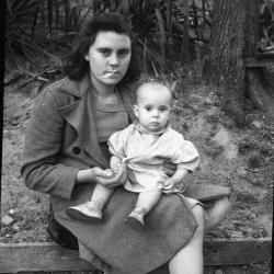 Woman sitting outdoors and holding a child