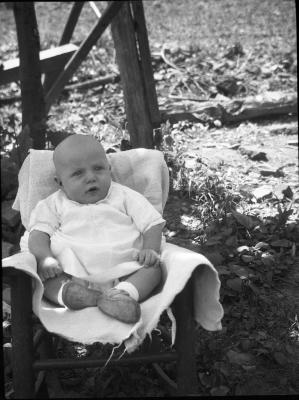 Baby posed for a photo in a chair outdoors
