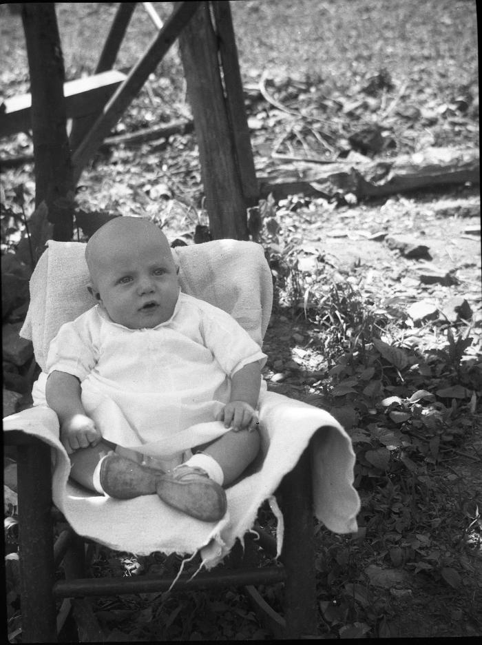 Baby posed for a photo in a chair outdoors
