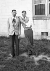 Two men posing in front of a building