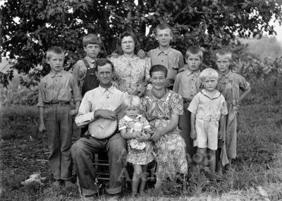 Exterior portrait of large family, man holding banjo