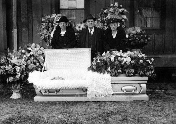 Three people standing with an open casket