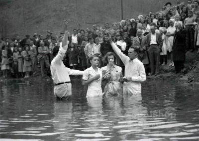 Young woman is baptized by two preachers