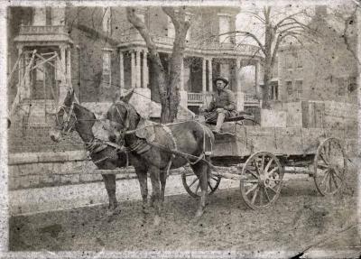 Man driving horse-drawn cart down main street
