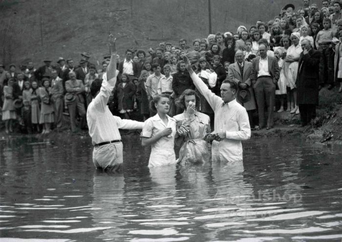 Young woman is baptized by two preachers