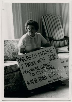 Production still of woman holding protest sign - The Struggle of Coon Branch Mountain