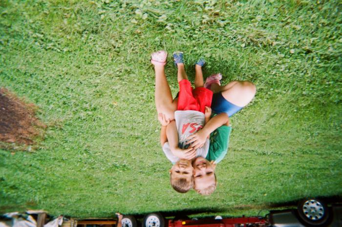 Girl hugging a young boy on lawn