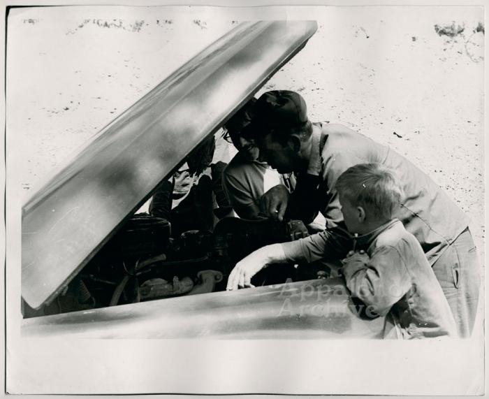 Production still of men under car hood - The Struggle of Coon Branch Mountain