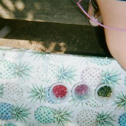 Cups filled with colorful beads on a pineapple tablecloth