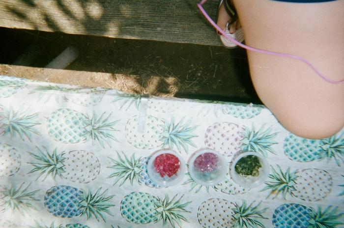 Cups filled with colorful beads on a pineapple tablecloth