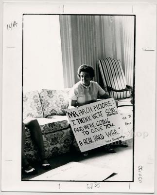Production still of woman holding protest sign - The Struggle of Coon Branch Mountain