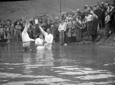 Woman in white getting baptized in river