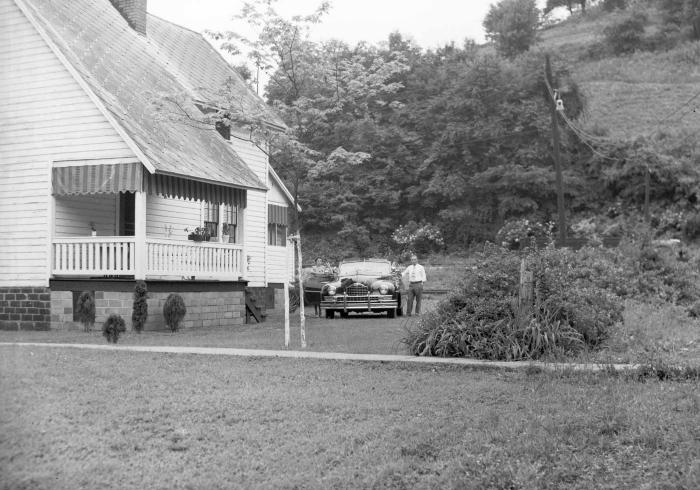 Couple posing with car in side yard