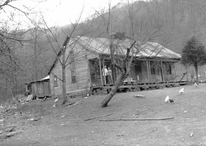 Couple and white dog on the porch of a home