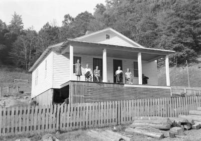 Group portrait on porch, five sitting, one standing