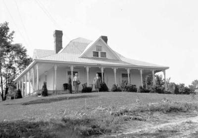 Older couple standing in front of house with ornate columns