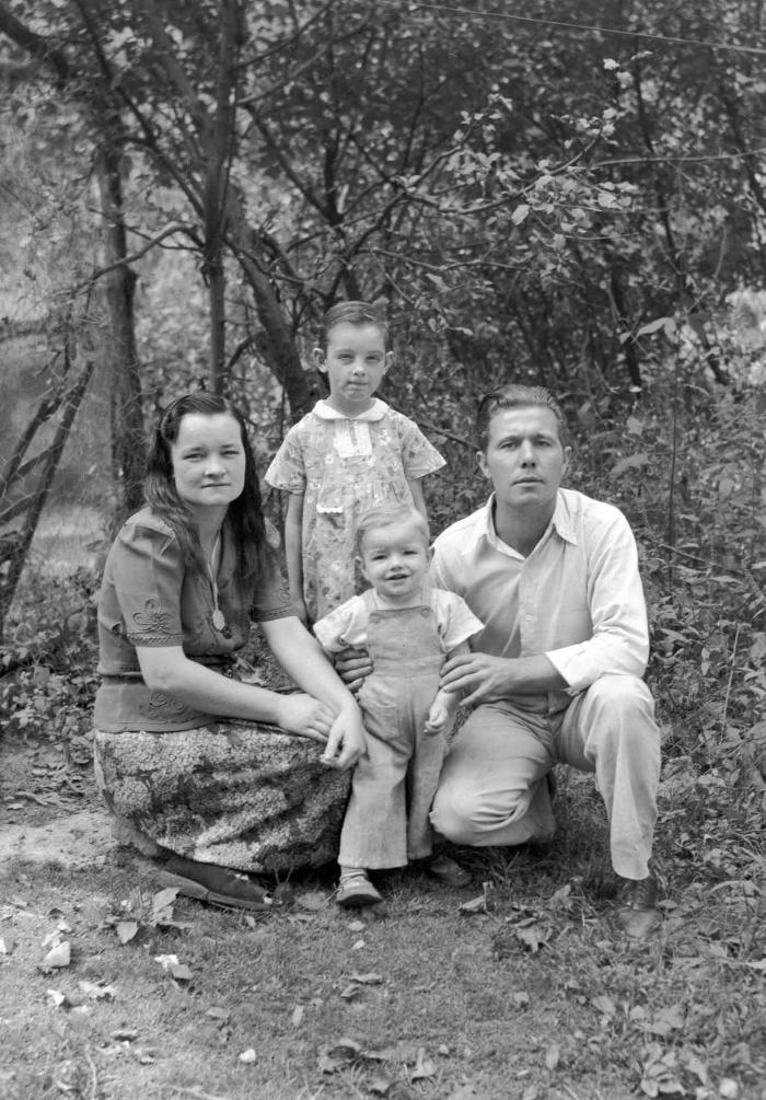 Group portrait of couple crouching in wooded area with two children