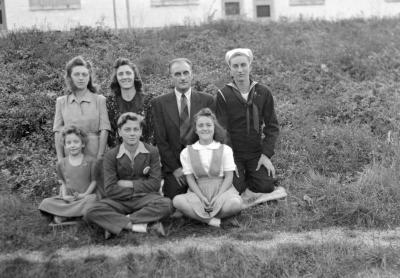 Group portrait of family sitting, kneeling in grass
