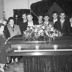 Group portrait in funeral parlor surrounding casket