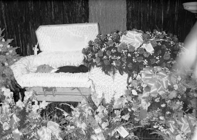 Man in casket with rose floral spray