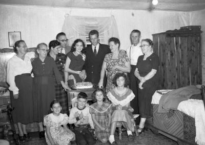 Group portrait of family with couple cutting cake