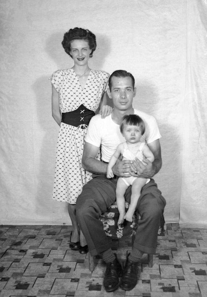 Interior portrait of family against patterned linoleum floor and cloth backdrop