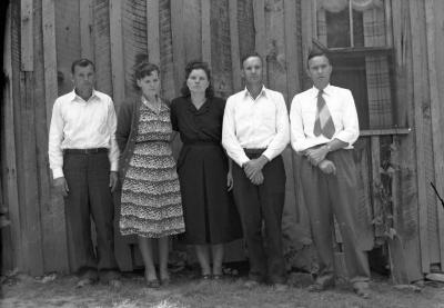 Group of five posing against house with wooden siding