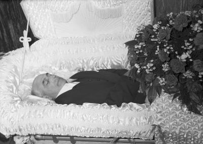 Portrait of man in casket with rose floral spray