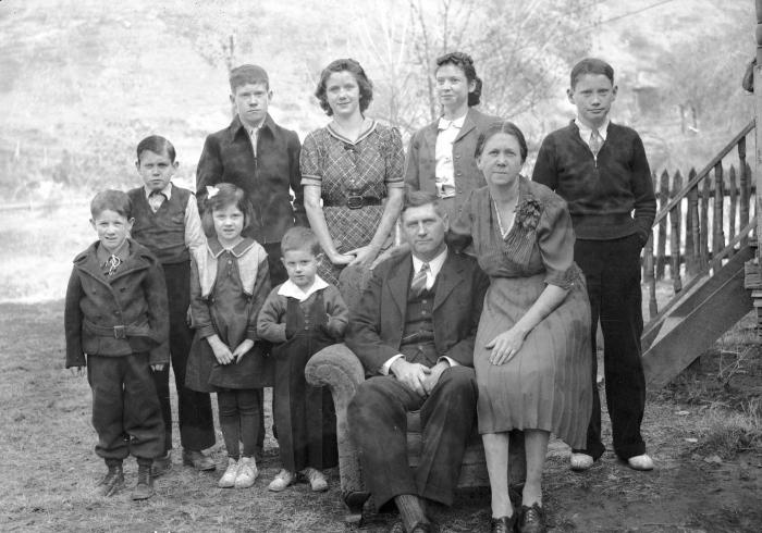 Group portrait of family of ten, father and mother seated on armchair