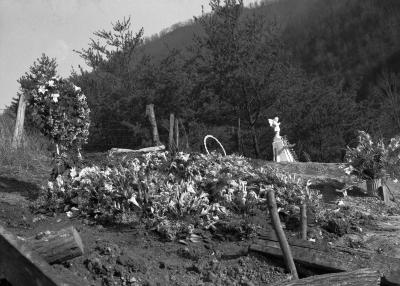 Mountainside gravesite with floral arrangements