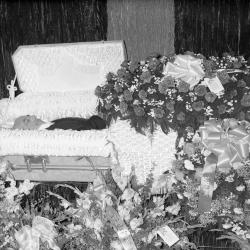 Man in casket with rose floral spray