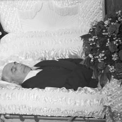 Portrait of man in casket with rose floral spray