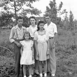 Family of five with styled hair poses amidst foliage
