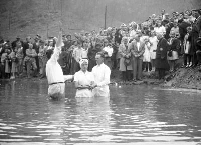 Woman in headscarf getting baptized in river