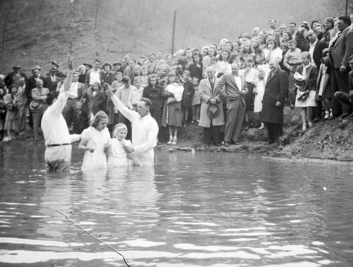 Two children getting baptized in river