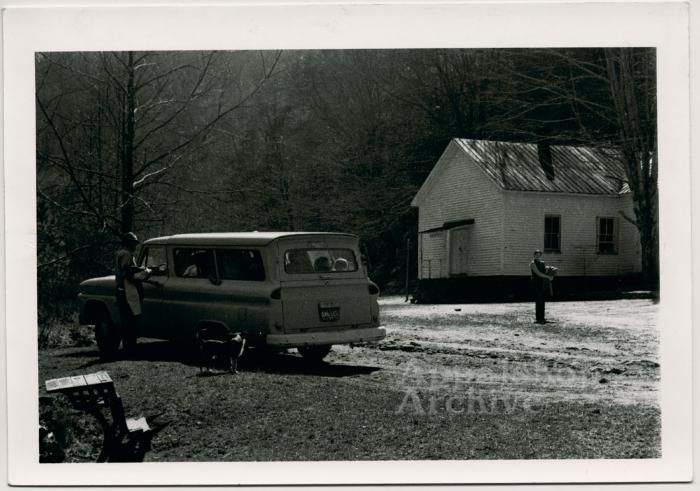 Production still of car and school building - Kingdom Come School