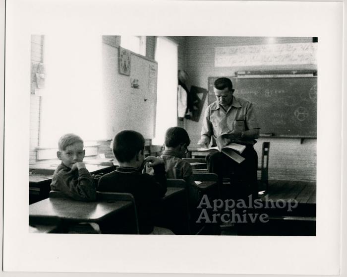 Production still of three children and a teacher in a classroom - Kingdom Come School