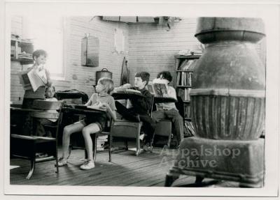 Production still of classroom with children and wood-burning stove -Kingdom Come School